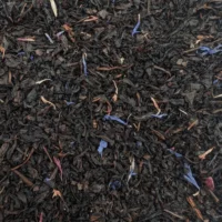 Magie de Noël : Photo du thé vu de haut. Thé noir à feuilles fines décoré de jolis pétales de fleurs bleus et rouges.