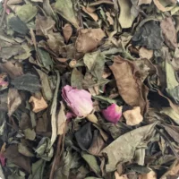 Photo du thé blanc rose framboise vu de près. Les feuilles de thé blanc sont grandes, peu travaillées. Il est agrémenté de boutons de roses et de poivre rose.