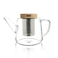 Photo de la théière en verre OGO - 1L. Le verre est transparent, la théi!ère est arrondie en bas et se rétrécie en remontant. Le bec verseaur remonte pratiquement en vertical. Le filtre en acier inoxydable est apparent ainsi que le couvercle en bois.