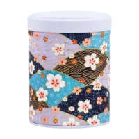 Photo de la boîte à thé empilable - Falkia Repens : papier washi fond en forme d'éventails bleus, violets, noirs, petites fleurs blanches et rouges. Boîte ronde, couvercle blanc.