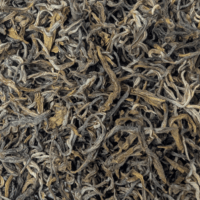 Photo du thé jaune Yunnan Mao Feng vu de haut. Feuilles longues, torsadées, nuancées dans les tons vert, marron et gris.