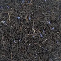 Vue de haut du thé noir bio Ceylan Litchi montrant ses belles feuilles torsadées parsemées de pétales de bleuet rouge et de bruyère